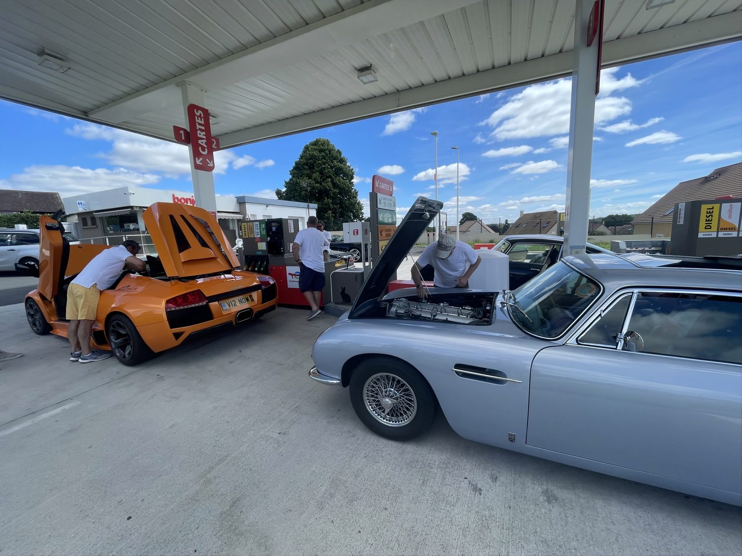Cars with their bonnets up being worked on in a garage